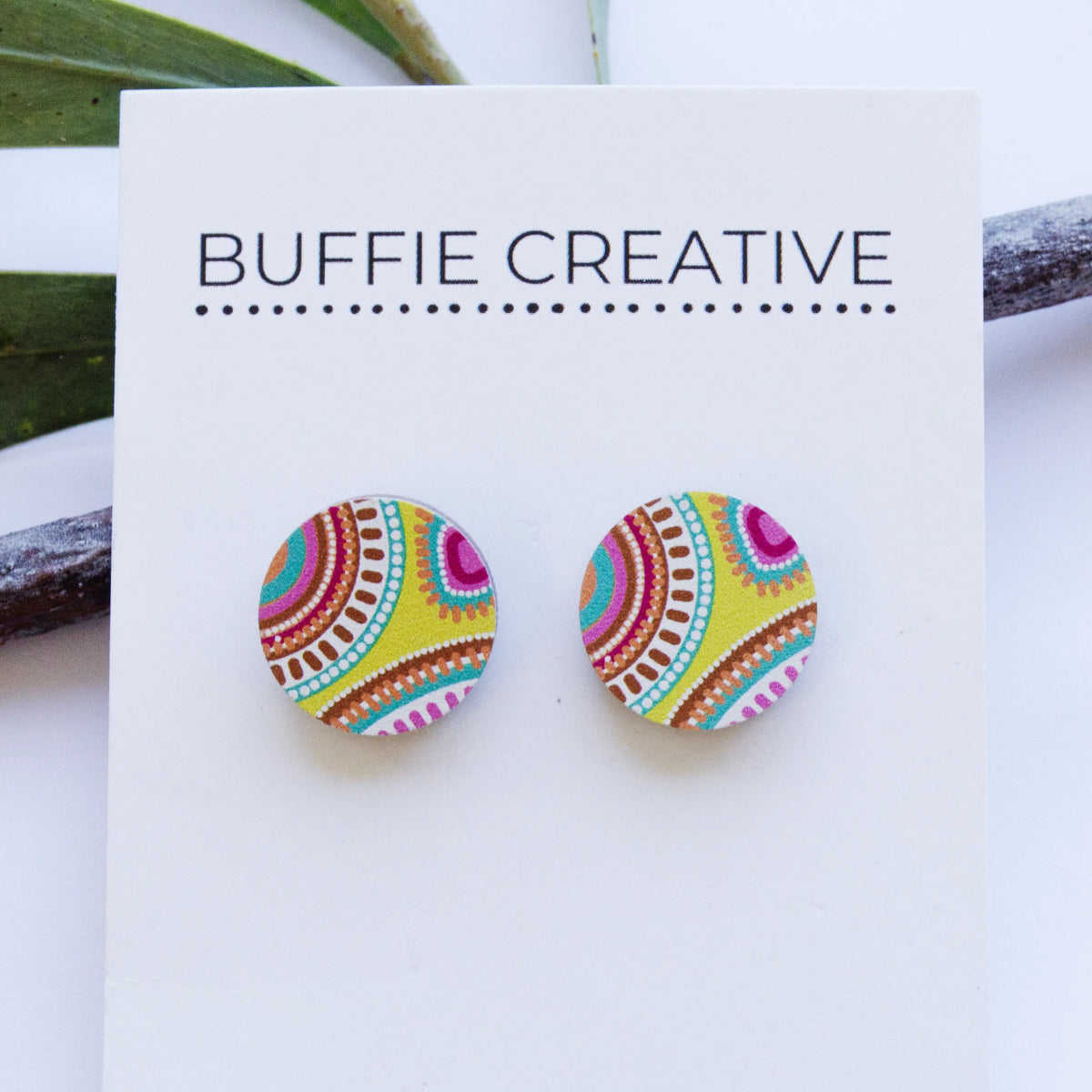 Round Yellow Pattern Stud Earrings on Buffie Creative card packaging, featuring a vibrant yellow, turquoise, magenta pink, and earth-toned Indigenous art motif, designed by Buffie Punch.